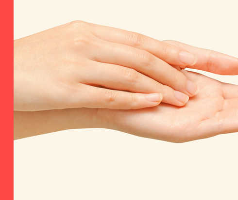 Psoriasis: Psoriasis-Arthritis Zwei Hände einer Person liegen übereinander. Die obere Hand streicht über die Innenfläche der unteren Hand.