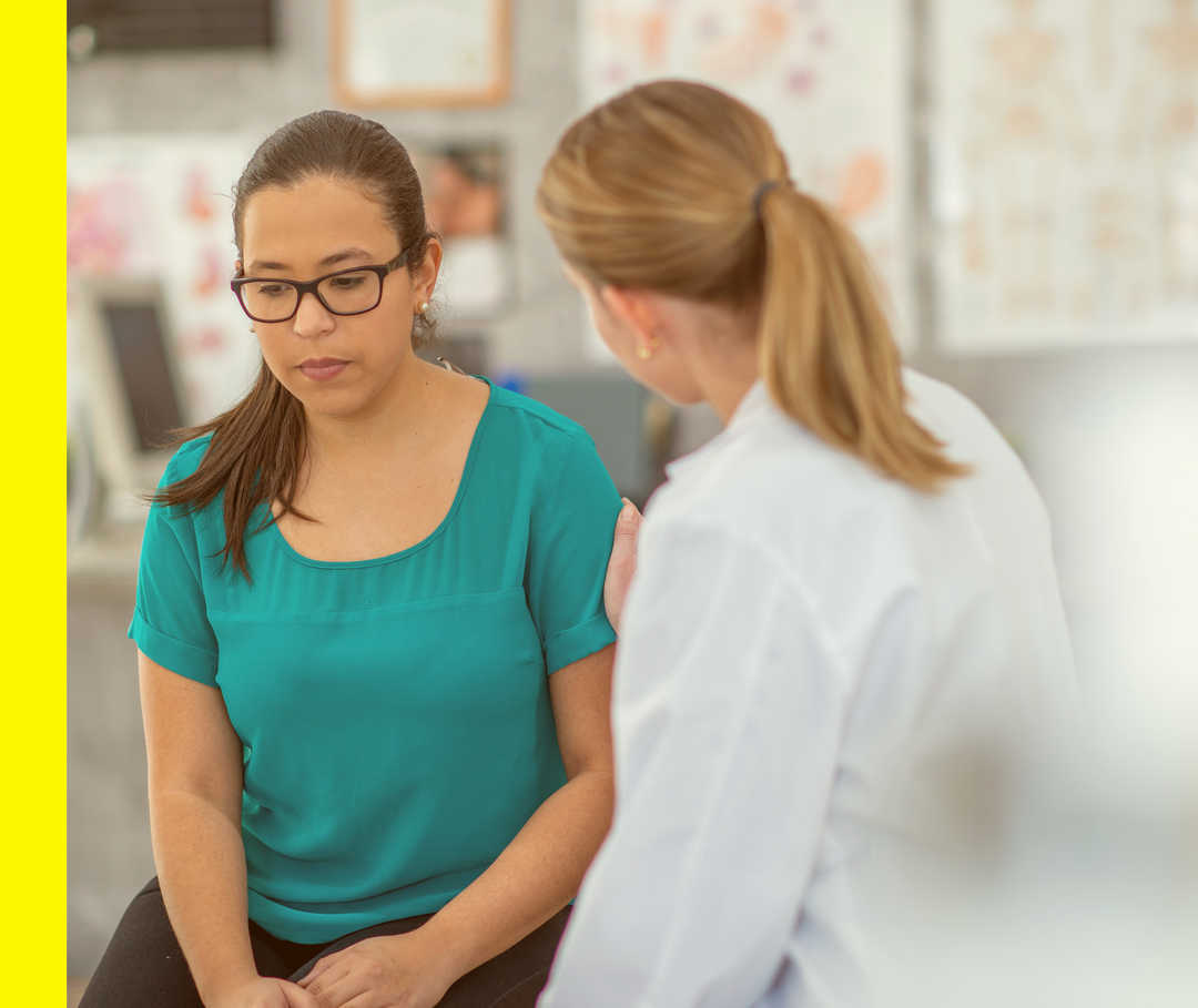 Akne inversa: Schmerzen Eine Ärztin muntert ihre Patientin in einem Gespräch auf