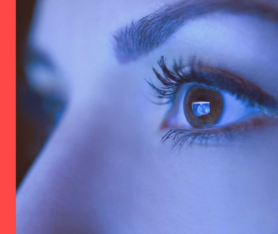 Hautwende erleben: blaues Bildschirmlicht Nahaufnahme eines Gesichts mit Fokus auf einem geöffneten Auge, das in blaues Licht schaut.