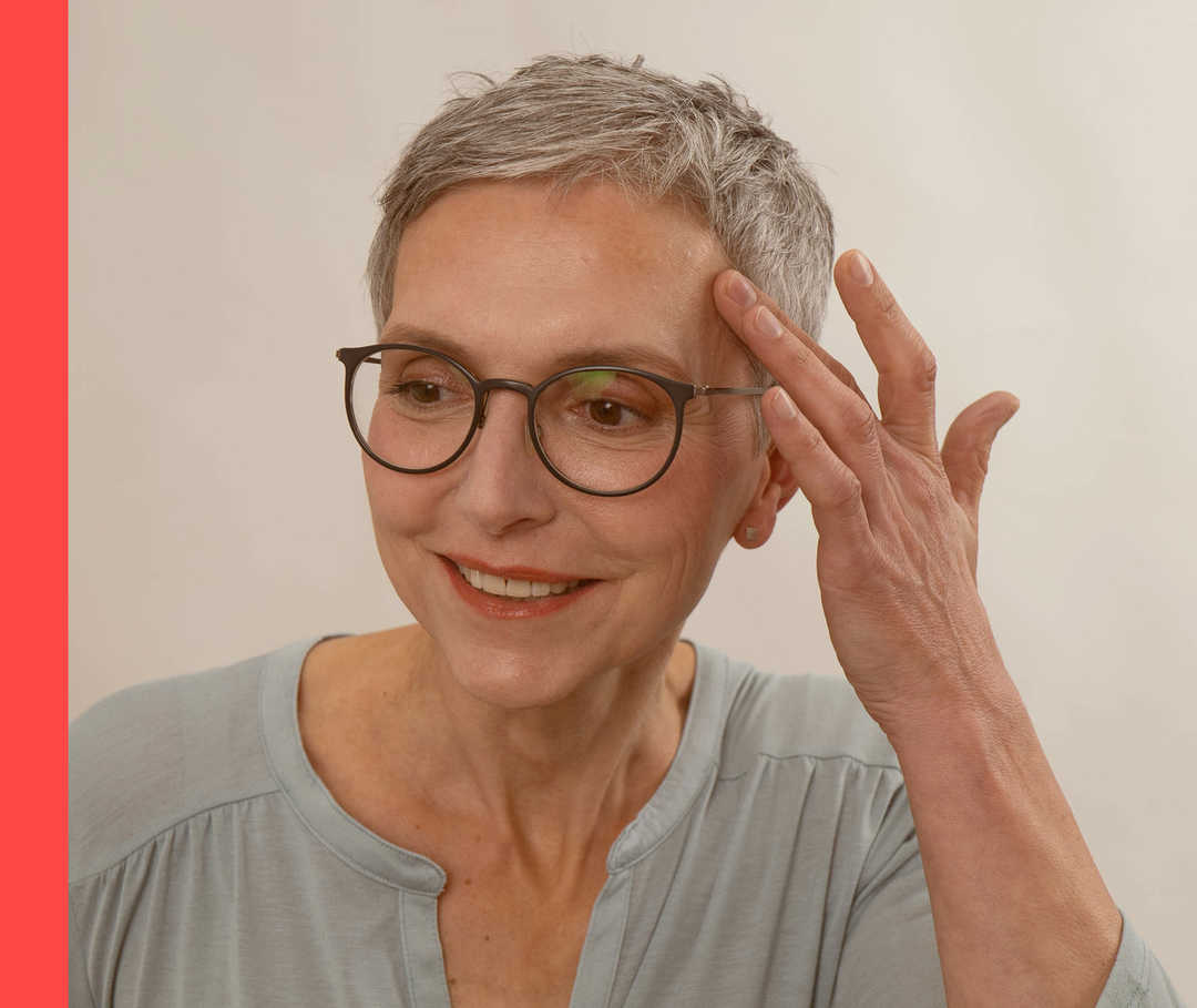 Lichttherapie gegen Schuppenflechte Eine Frau streicht sich über ihre Stirn und lächelt.