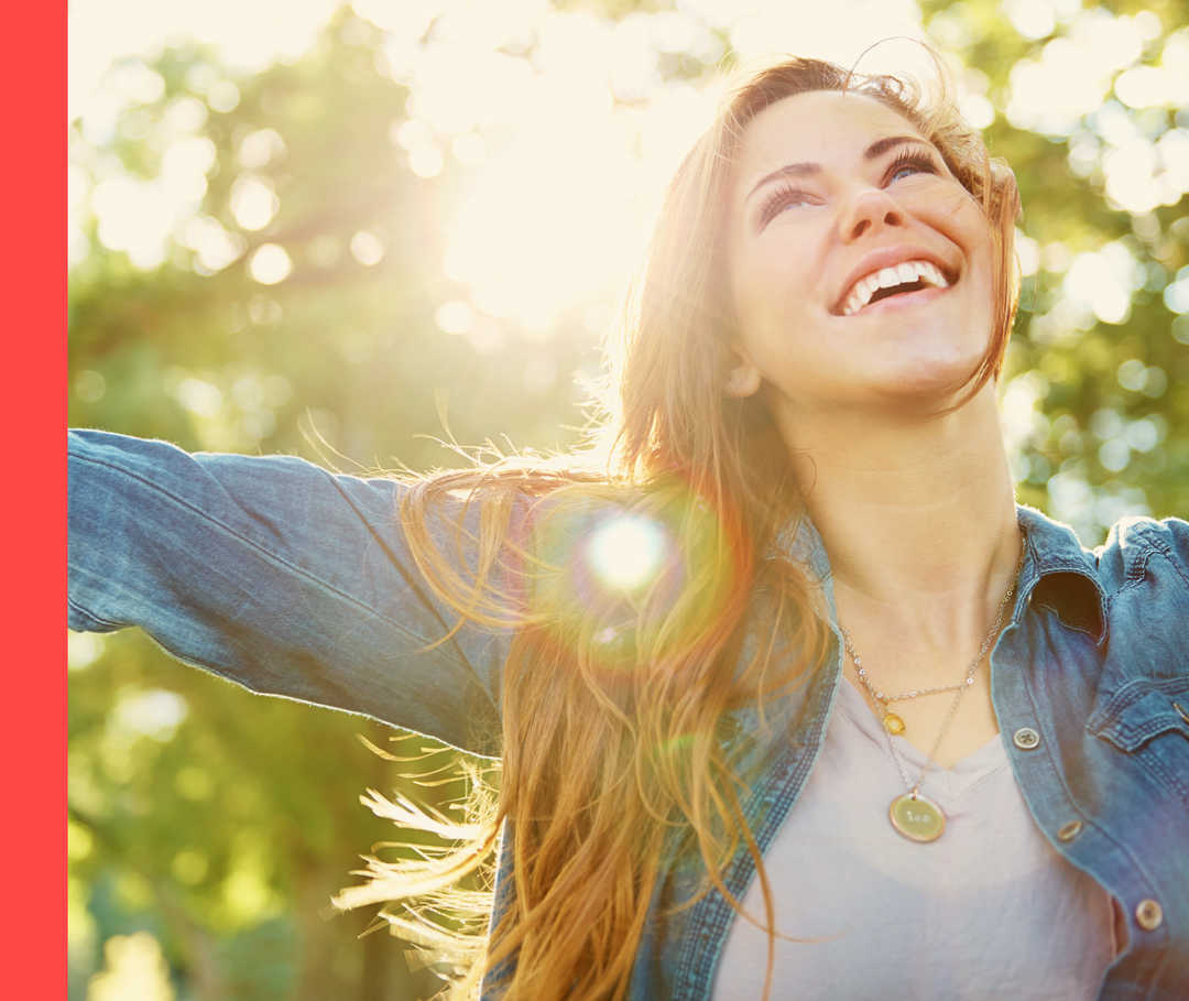 Psoriasis: Vitamin D und Sonne Eine Frau steht in der Natur und streckt die Arme in den Himmel.