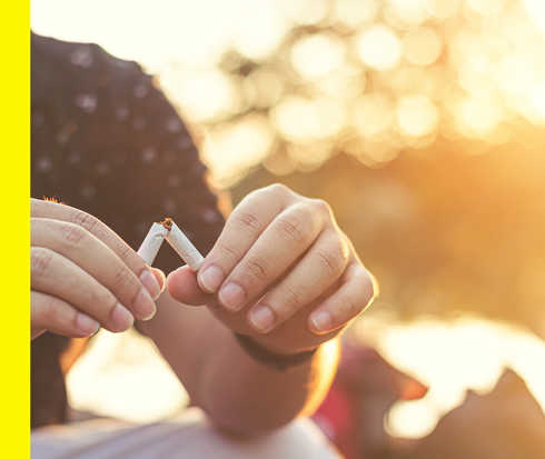 Bildausschnitt von zwei Händen, die eine Zigarette zerbrechen.