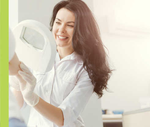 Eine Frau in weißem Kittel betrachtet den rechten Oberarm einer weiteren Person durch eine Lupe.