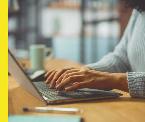 Bildausschnitt einer Person, die auf einem Notebook tippt.
