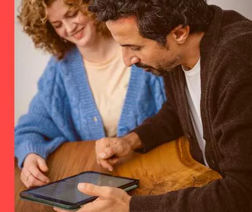 Ein Mann und eine Frau schauen auf einen Tablet-PC.