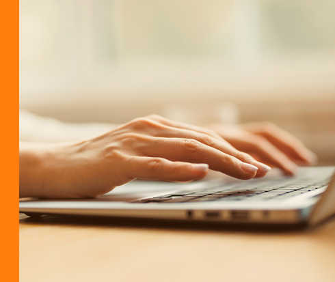 Zwei Hände einer Person, die auf einem Notebook tippt.