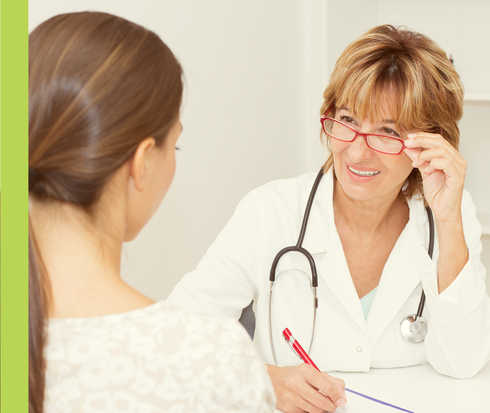 Eine Frau im weißen Kittel im Gespräch mit einer weiteren Person.