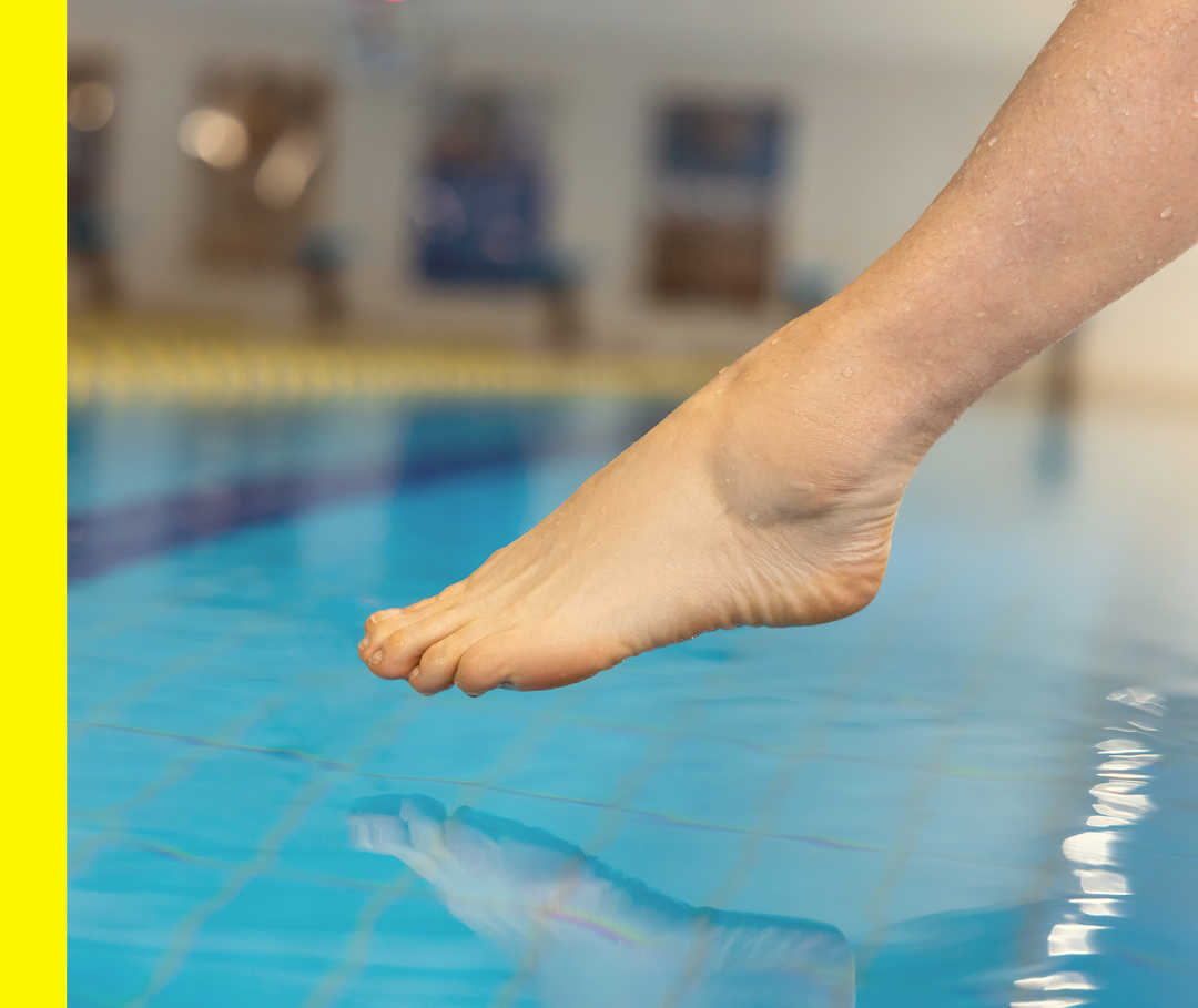 Nahaufnahme eines Fußes über der Wasseroberfläche eines Schwimmbads.