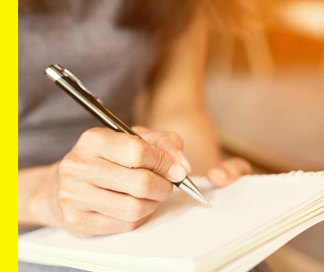 Nahaufnahme von zwei Händen, die einen Stift und einen Notizblock halten.