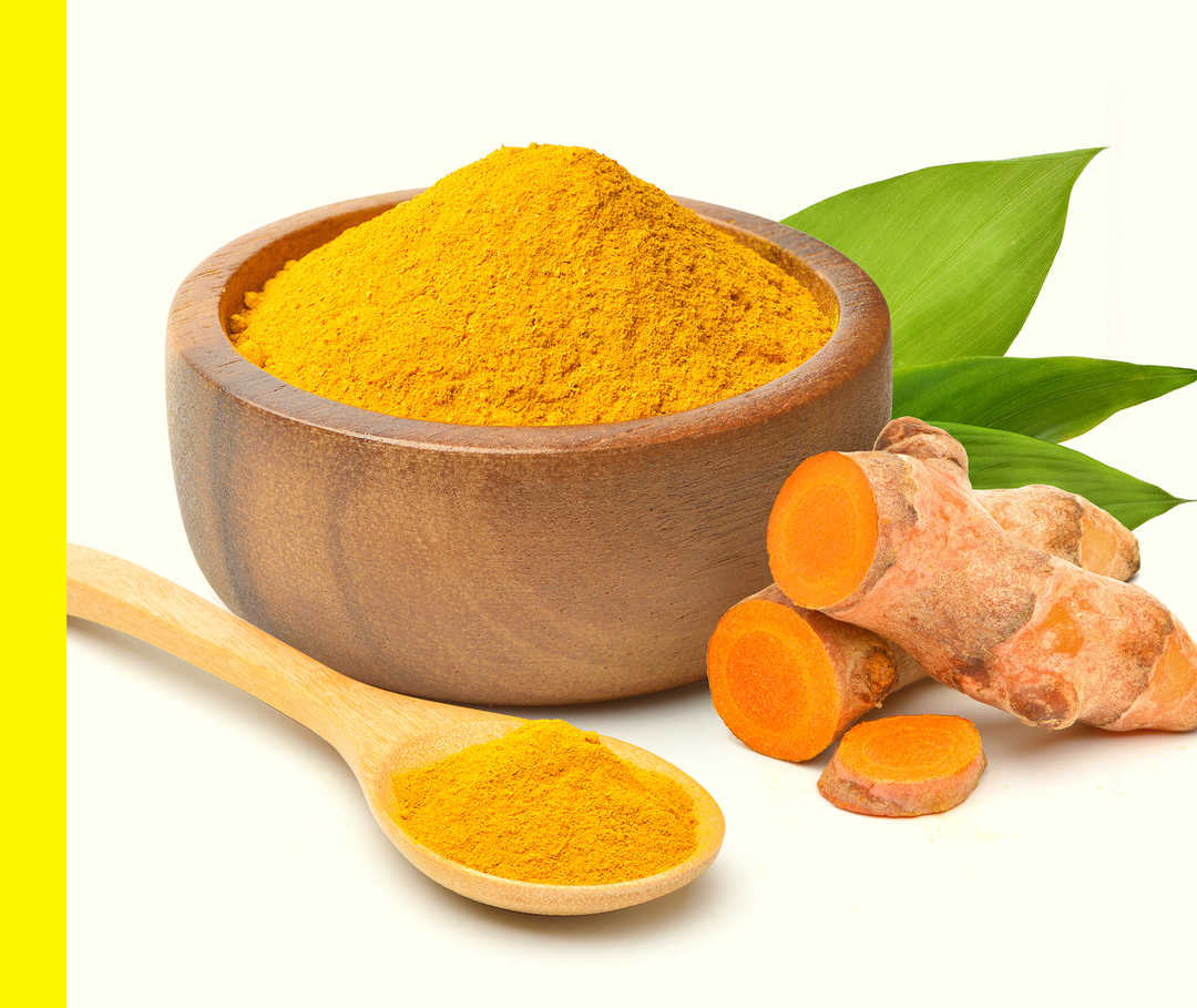 Ein Kochlöffel und eine Schale orangenem Pulver sowie Blätter und eine zerschnittene Wurzel.