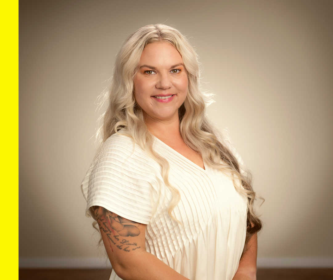 Rabea steht im Licht und lächelt freundlich in die Kamera.