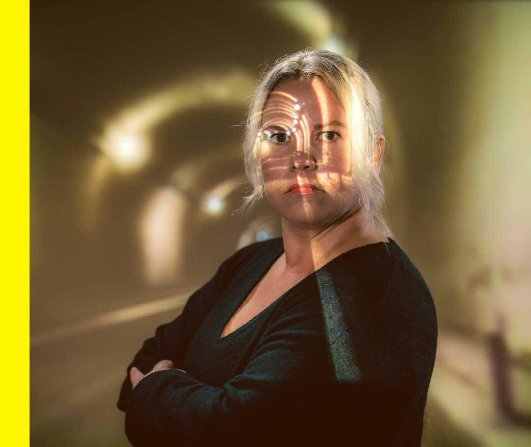 Rabea steht in einem düsteren Tunnel und schaut mit einem ernsten Gesichtsausdruck in die Kamera.