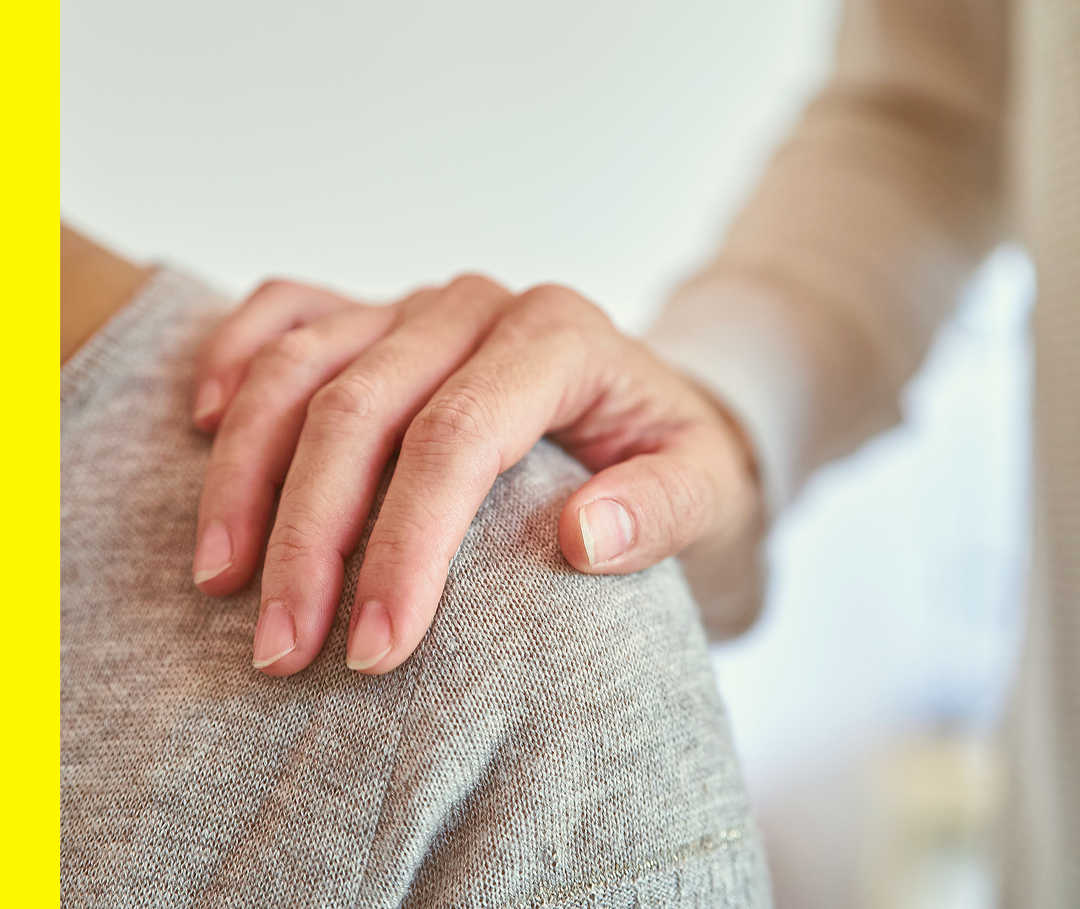 Nahaufnahme einer Hand, die auf der Schulter einer anderen Person liegt.