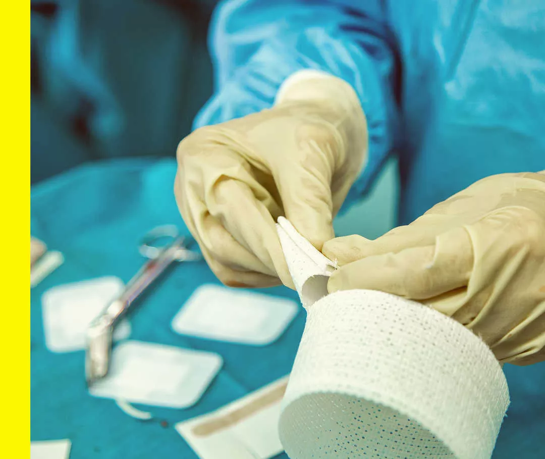 Ein Arzt hält ein Wundpflaster am Operationstisch in der Hand.