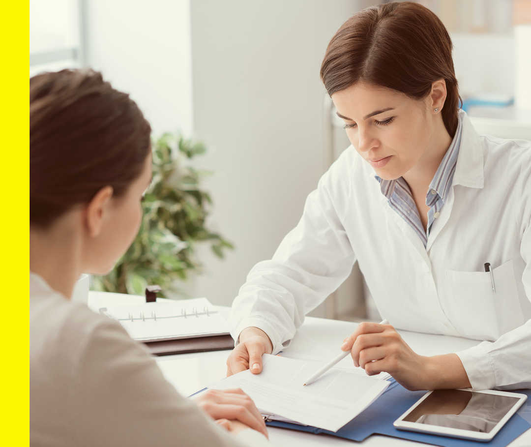 Eine Ärztin zeigt ihrer Patientin etwas in ihren Notizen