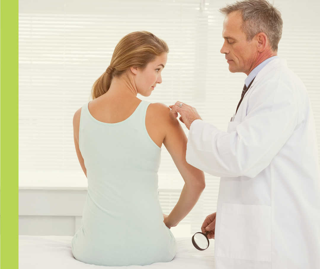 Ein Mann untersucht die rechte Schulterpartie einer Frau.