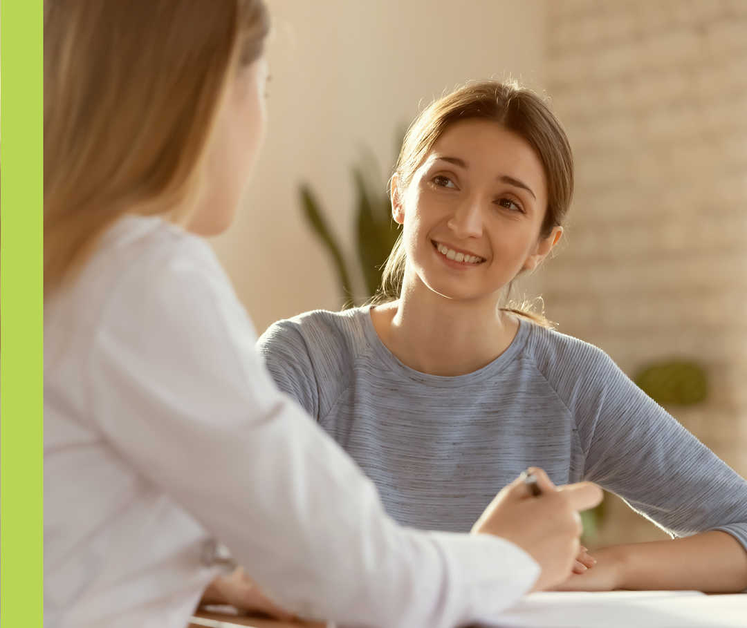 Eine Frau im Gespräch mit einer anderen Frau, die einen weißen Kittel trägt.