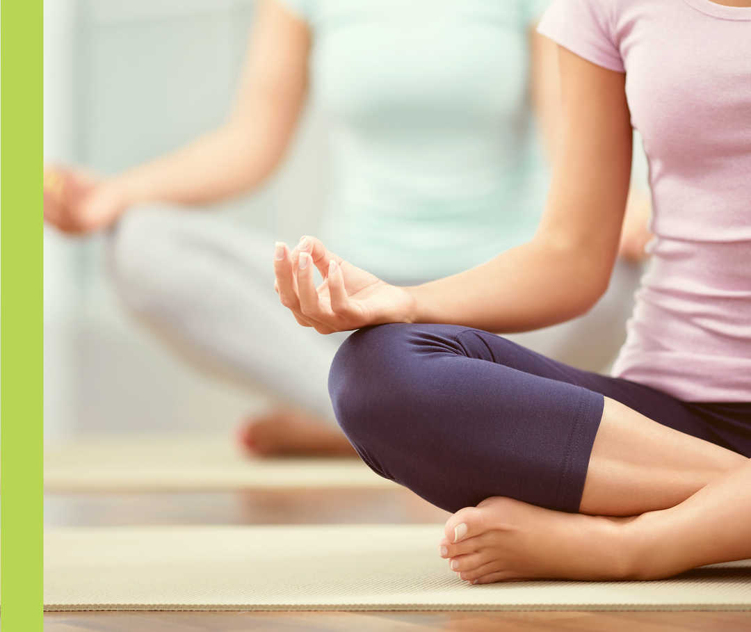 Zwei Frauen sitzen im Lotus-Sitz auf dem Boden.