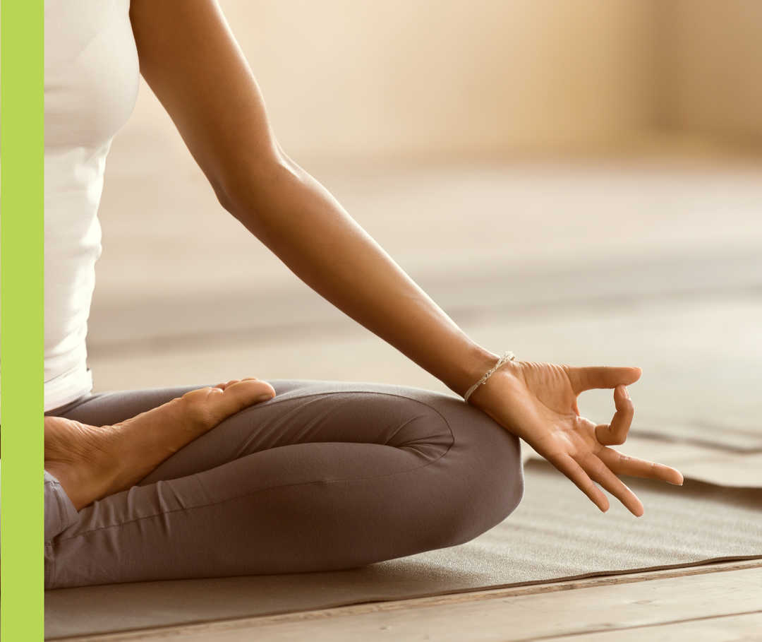 Eine Frau sitzt entspannt im Schneidersitz beim Yoga.