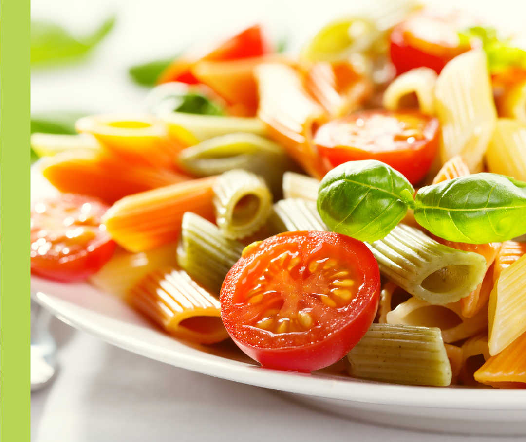 Ein Teller mit Pasta, Tomaten und Basilikum.