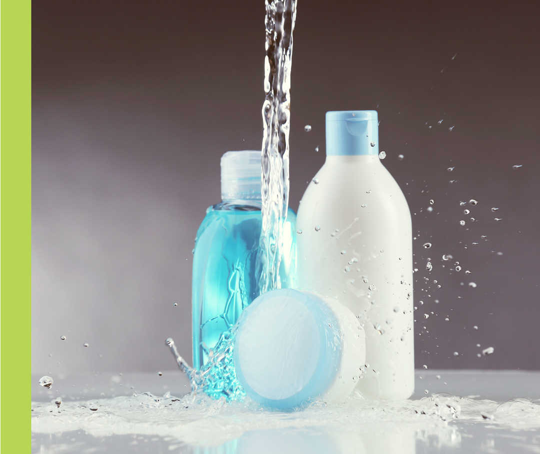 Wasser prasselt auf zwei Kosmetikflaschen und eine Plastikdose.