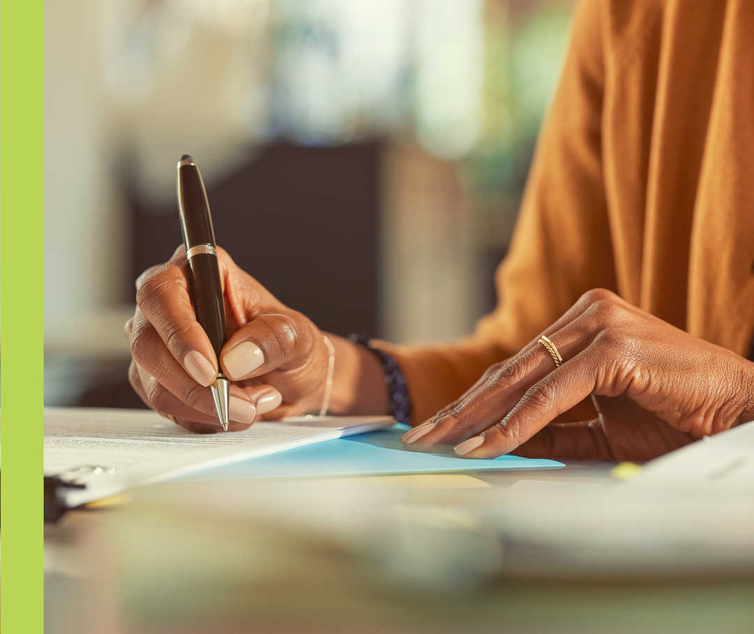 Eine Person schreibt mit einem Kugelschreiber auf Papier.