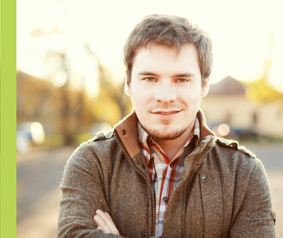 Ein Mann mit Jacke und hohem Kragen schaut lächelnd in die Kamera.