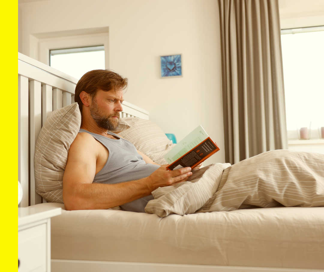 Ein Mann ruht sich in seinem Bett aus und liest etwas