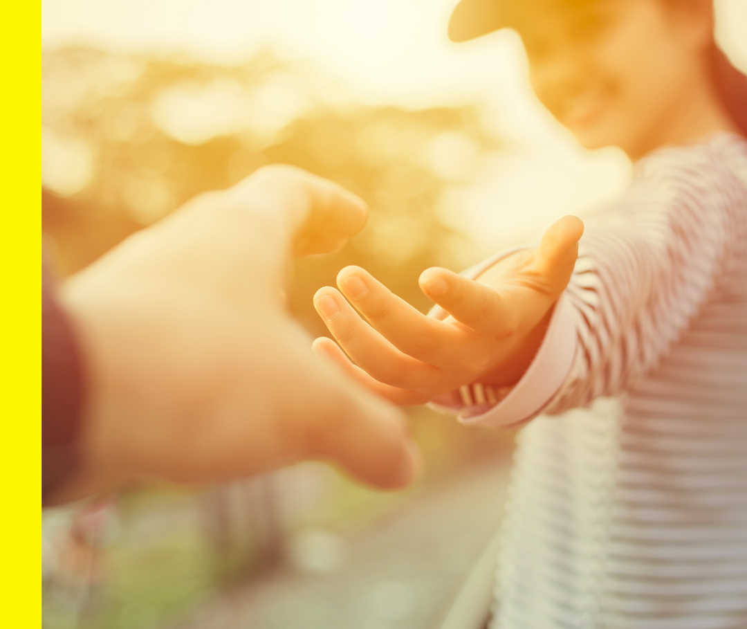Nahaufnahme einer Hand, die nach der Hand einer anderen Person greift.