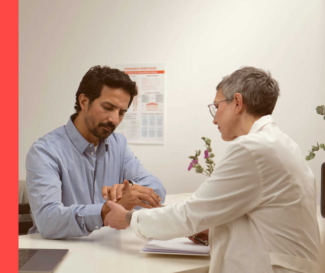 Eine Ärztin hält das Handgelenk eines Mannes und betrachtet es.