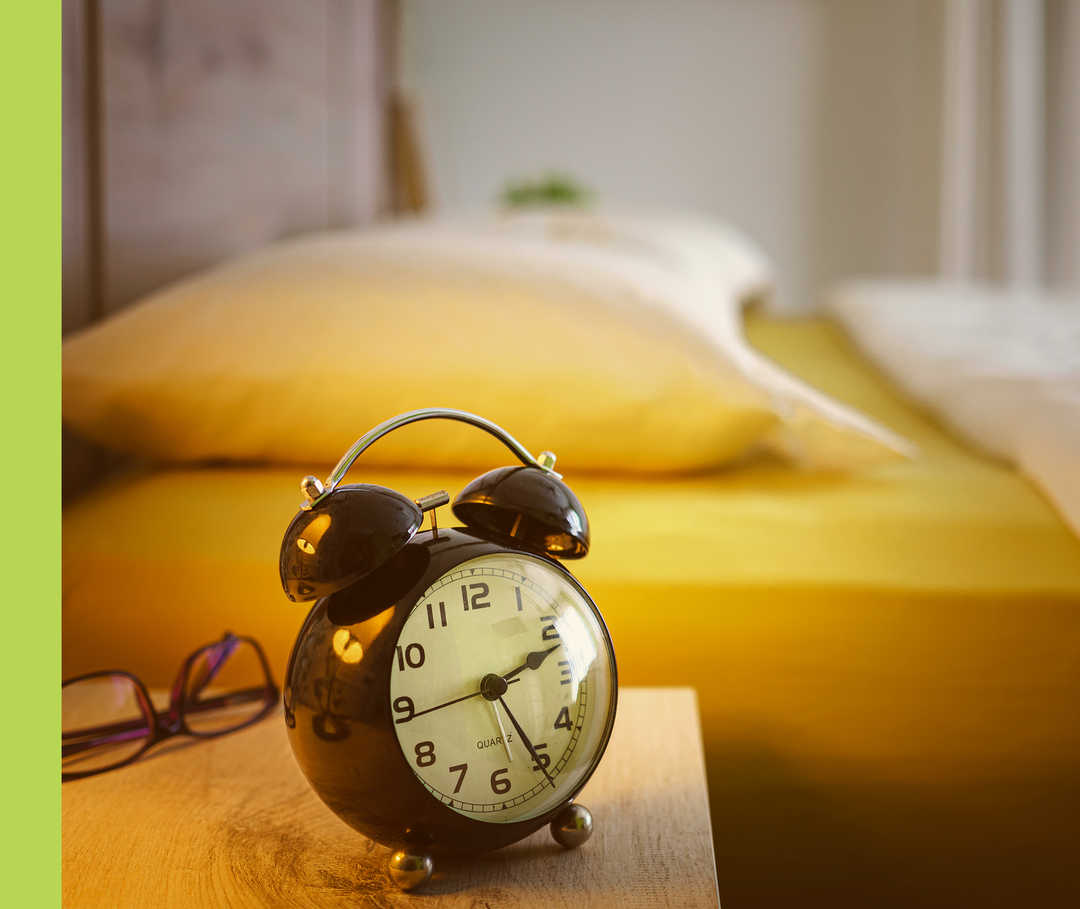 Nahaufnahme eines Weckers auf einem Nachttisch.