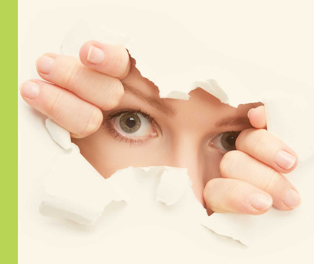 Zwei Augen spähen durch ein Loch im zerrissenen Papier.