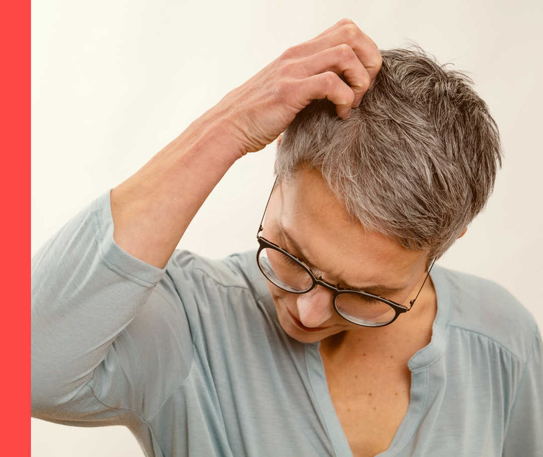 Eine Frau kratzt sich am Kopf. 