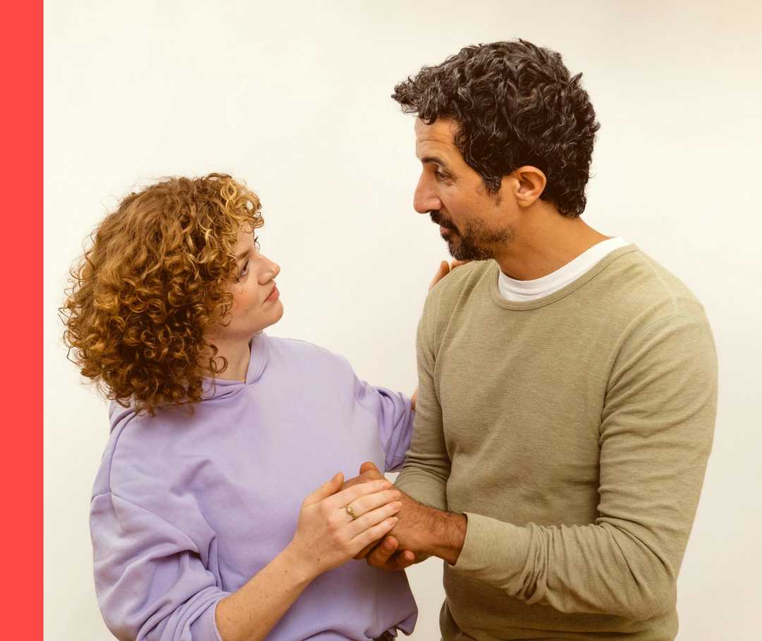 Eine Frau und ein Mann halten sich an der Hand und schauen sich an.