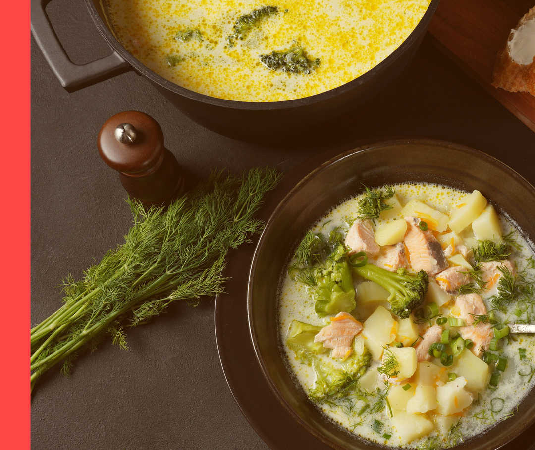 Angerichtete Suppe in einer Schüssel mit Brokkoli, Kartoffeln und Lachs, daneben Dill und Baguette.
