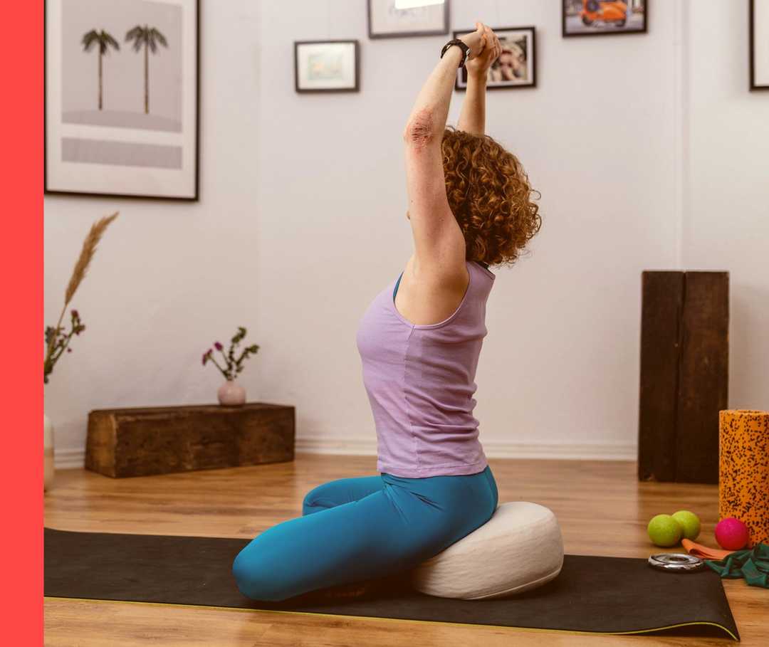 Eine Frau sitzt auf einer Matte und macht Yoga.