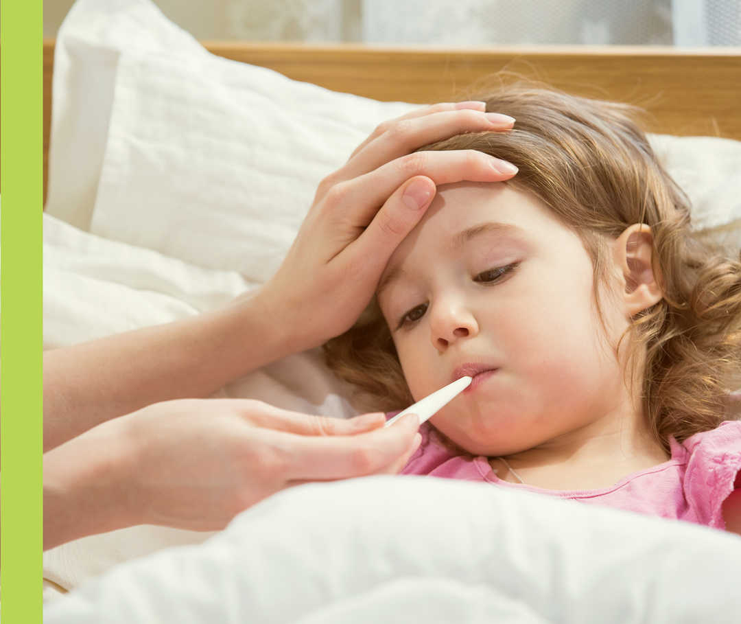 Eine Person misst einem kleinen Mädchen die Körpertemperatur mit einem Thermometer im Mund und streicht ihm über die Stirn. 