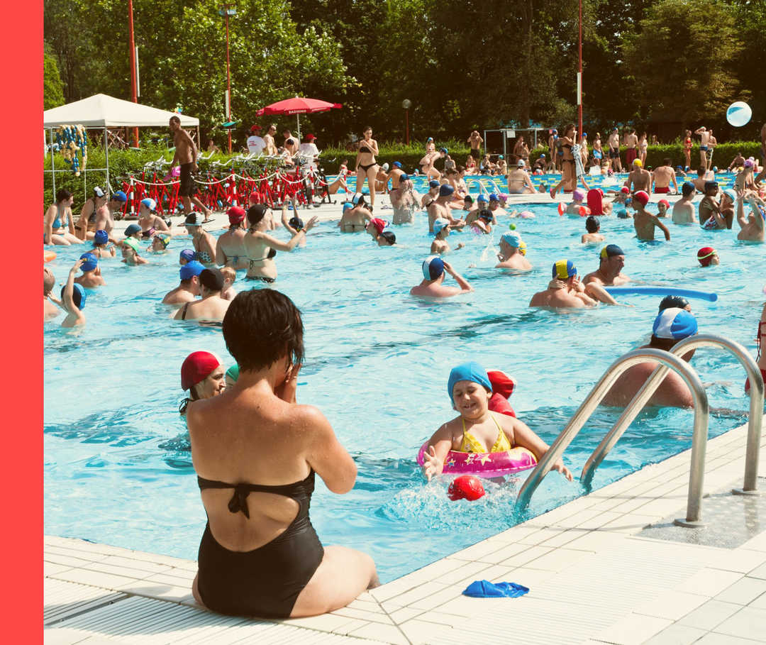 Volles Becken eines Freibads im Sonnenschein.