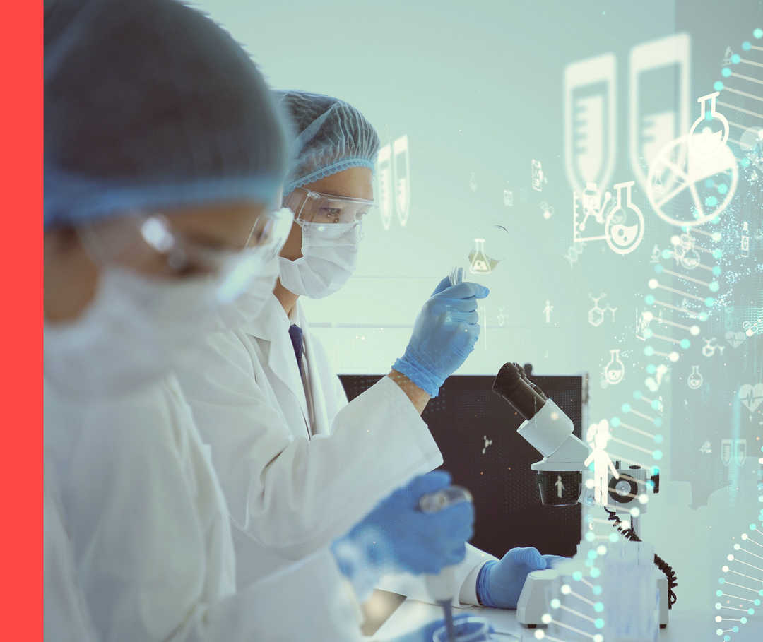 Zwei Personen mit weißen Kitteln und Schutzbrillen stehen vor einem Mikroskop. Im Hintergrund sind chemische Symbole zu erkennen.