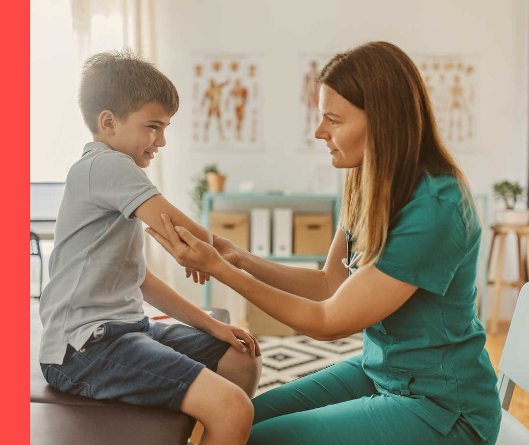 Eine Ärztin in grüner Kleidung sieht sich den Arm eines Jungen an.