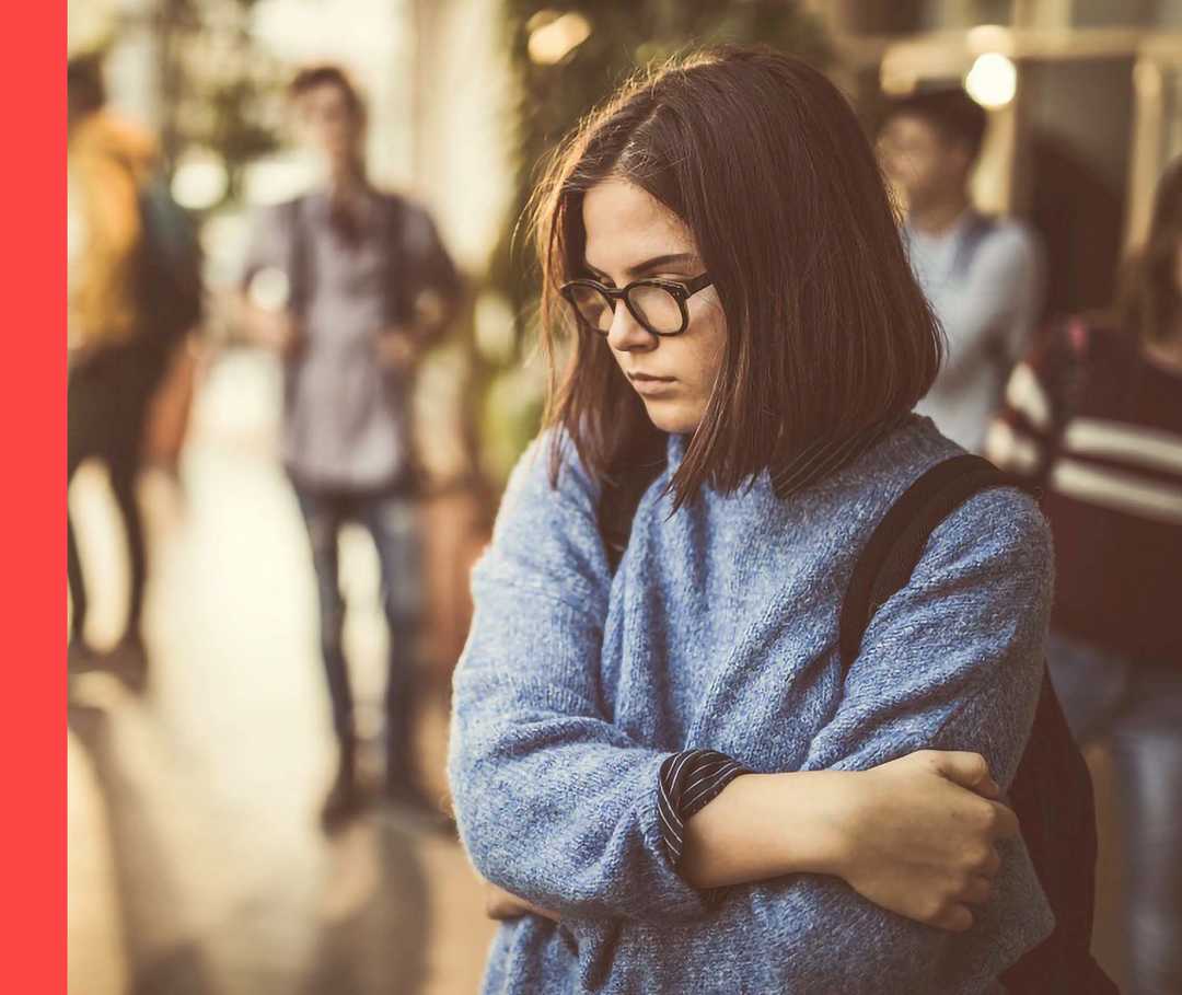 Jugendliches Mädchen umfasst mit beiden Armen ihren Oberkörper.