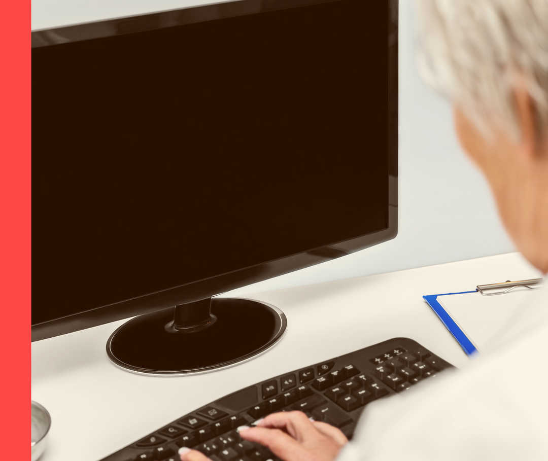 Nahaufnahme von einer Person in weißem Kittel, die vor einem Computer sitzt.