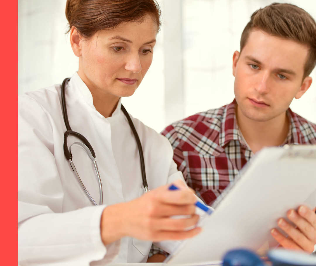 Eine Ärztin erklärt einem jungen Mann etwas auf einem Schriftstück.