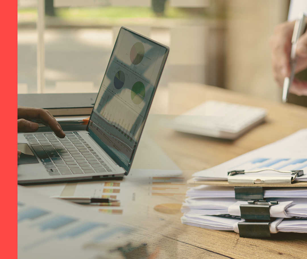 Ein Laptop, Diagramme und Unterlagen auf einem Tisch.
