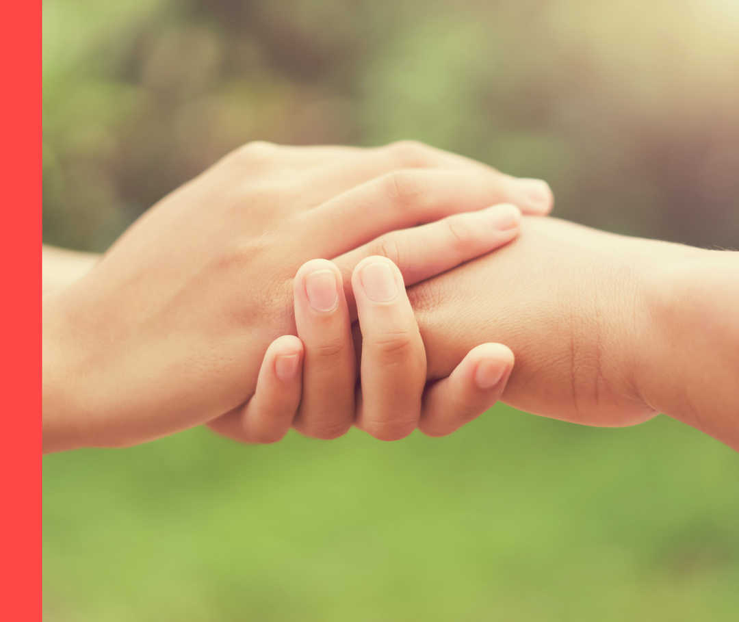 Nahaufnahme im Freien von zwei Händen, die eine andere Hand halten.