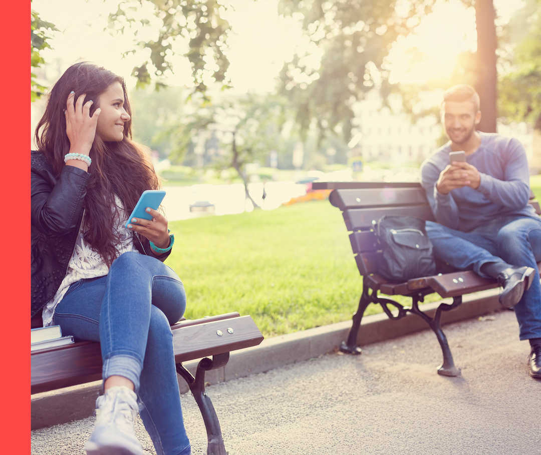 Ein Mann und eine Frau auf einer Parkbank flirten miteinander.