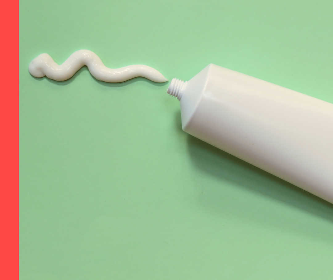 Eine weiße Tube und weiße Salbe vor hellgrünem Hintergrund.