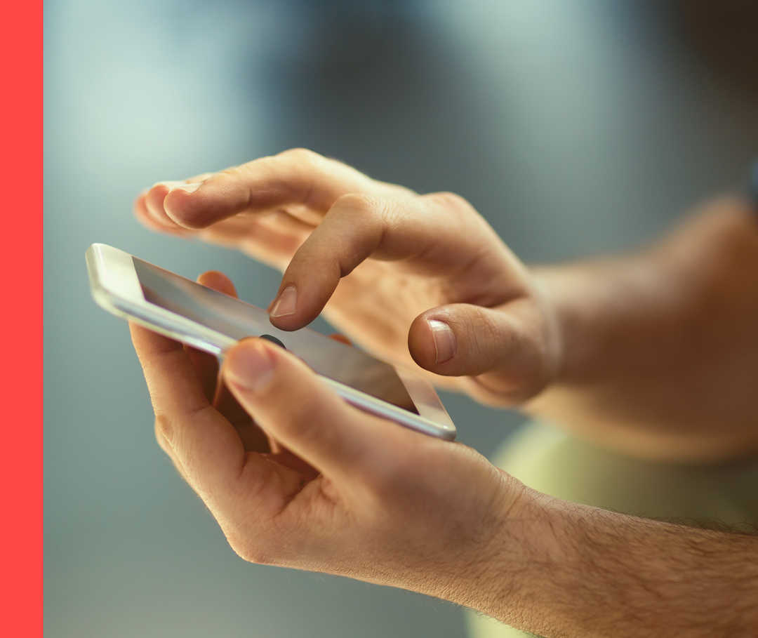 Eine Hand hält ein Smartphone, mit der anderen Hand wird darauf getippt.