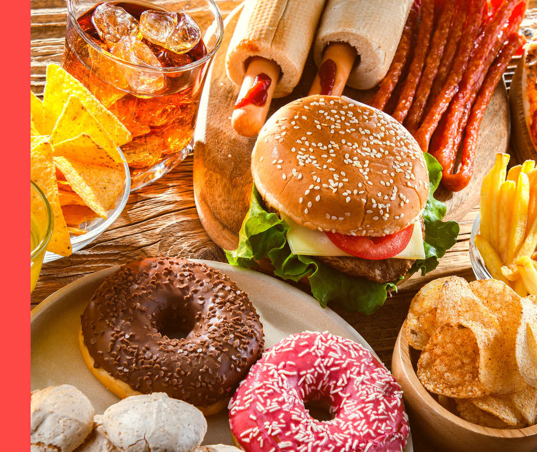 Auf einem Tisch sind viele Lebensmittel zu sehen, darunter Hamburger und Donuts.