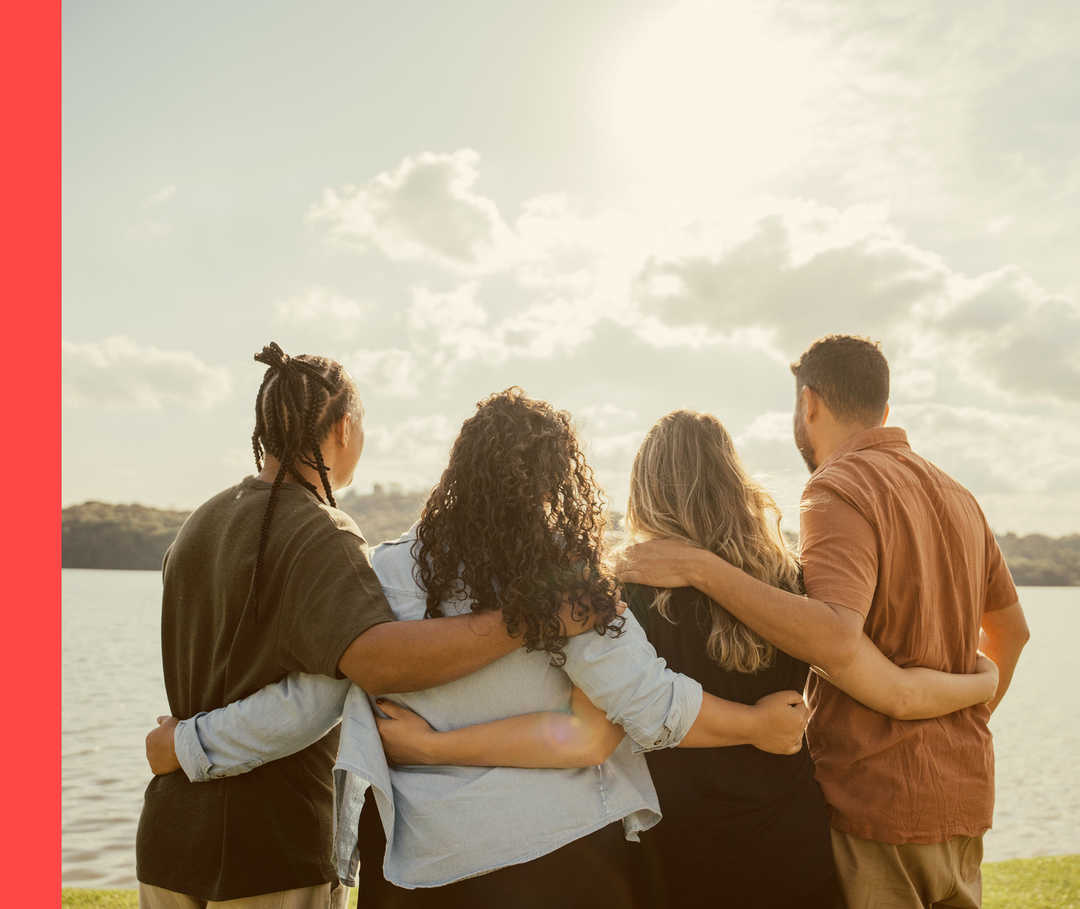 Vier Personen von hinten, die die Arme umeinander gelegt haben.